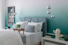 a stylish and bold bedroom with an ombre green accent wall, a grey upholstered bed, neutral bedding, pendant lamps and white nightstands