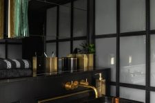 a stylish and luxurious powder room in black and gold, with gold framing and accessories plus a chic marble sink
