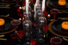 a stylish black, gold and red Halloween tablescape with red roses, candles, skulls, gold chargers and cutlery plus red drinks