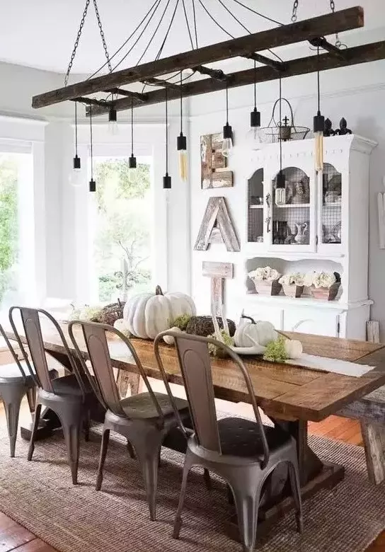 a vintage farmhouse meets industrial dining room with a white buffet, a wooden sign, a ladder with bulbs, a wooden table and metal chairs
