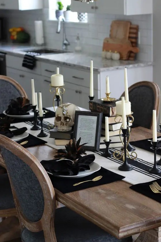 a vintage glam Halloween tablescape with a striped runner, stacks of books, candles in black candleholders, white porcelain and dark feathers