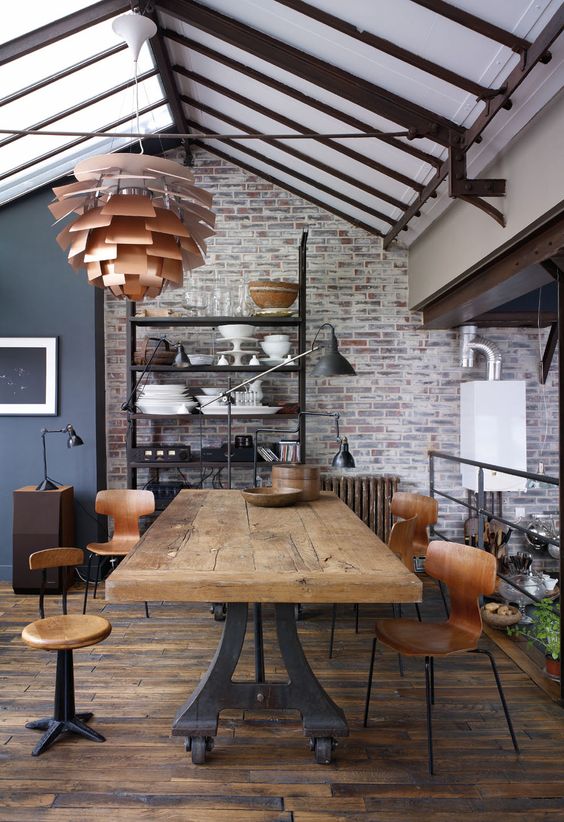 a vintage industrial dining space with a large metal and wood dining table, plywood chairs and stools, metal lamps and a pendant one