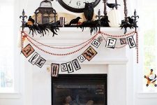 a vintage-inspired Halloween mantel with beads and banners, black feathers and blackbirds, cages, pumpkins, candles and a vintage clock