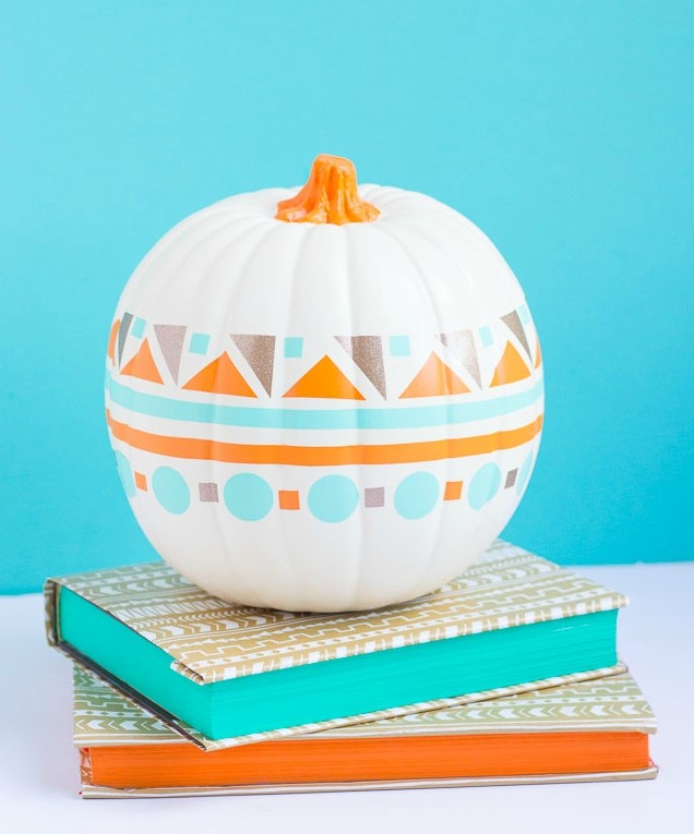 a white faux pumpkin decorated with stencils in bold colors will be a nice idea for a modern or boho Halloween party