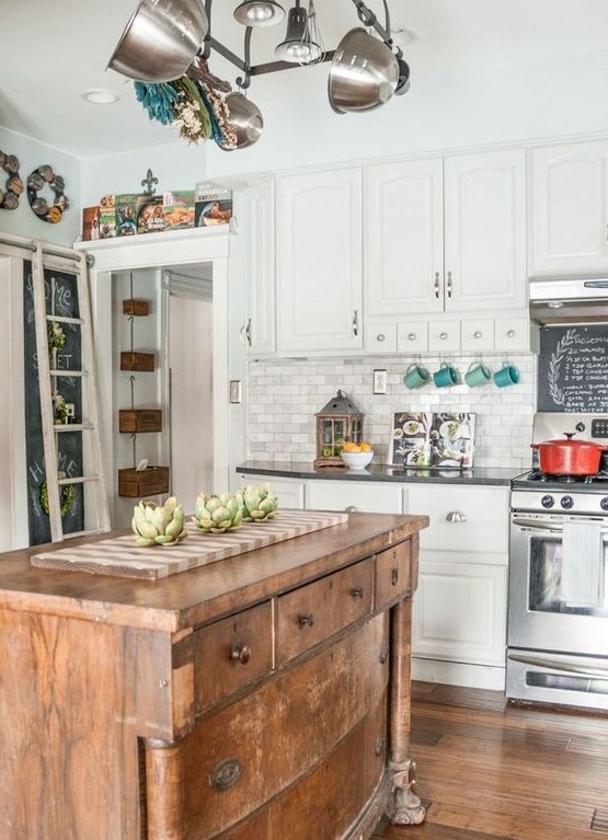 a white traditional kitchen with dark countertops spruced up with a vintage wooden kitchen island to make it more relaxed