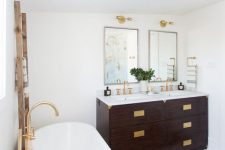 an art deco meets boho eclectic bathroom with lots of brass, boho rugs and a dark stained vanities