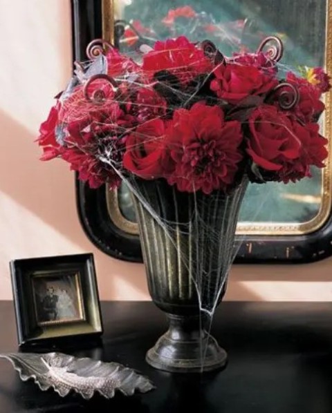 an easy Halloween arrangement of red roses and lotus swirls plus spiderwebs can become a centerpiece, too