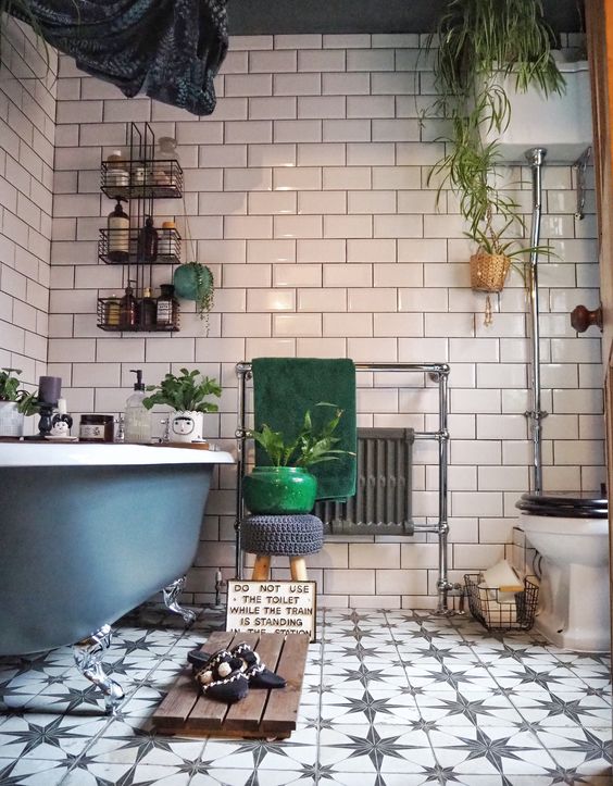 an eclectic bathroom with white and star printed tiles, a blue clawfoot tub, white appliances, potted greenery and green towels