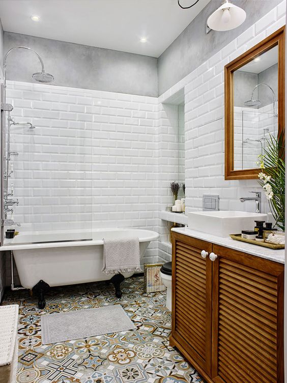 an eclectic bathroom with white subway and colorful tiles, a stained vanity, a clawfoot tub, a mirror in a stained frame