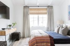 an eclectic bedroom with neutrals and various muted colors, mixed prints and mid-century modern furniture