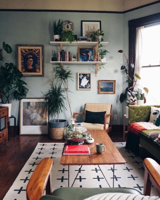 an eclectic living room with a gallery wall, open shelves, light blue walls, vintage furniture and potted greenery