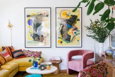 an eclectic living room with a yellow sofa and bright pillows, a bold printed rug, pink chairs, a colorful mini gallery wall and a stack of books