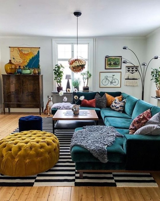 an eclectic living space with jewel tone furniture, a striped rug, a gallery wall and a vintage cabinet
