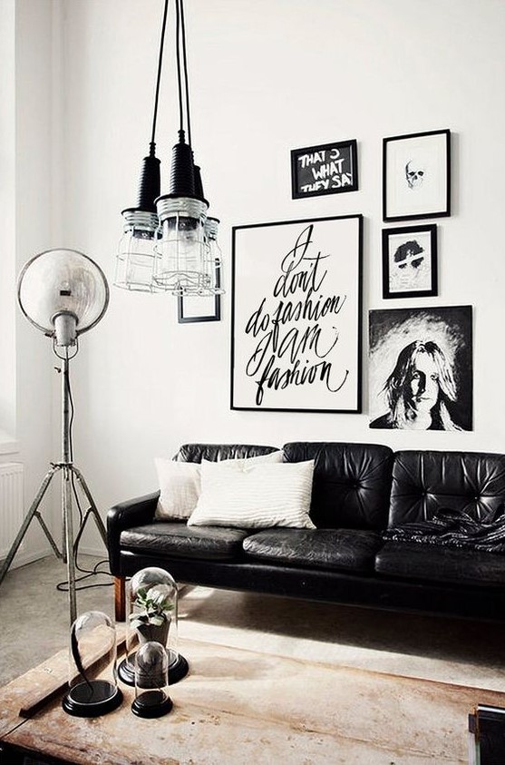 an edgy living room with a gorgeous gallery wall, a black leather sofa, a cluster of pendant lamps and a wooden coffee table