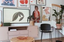 an ethereal living room with a blush credenza, a black chair and a round tiered table, a catchy free form gallery wall