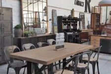 an industrial dining room with a large dining table on metal legs, matching chairs, a large metal pendant lamp and a metal credenza