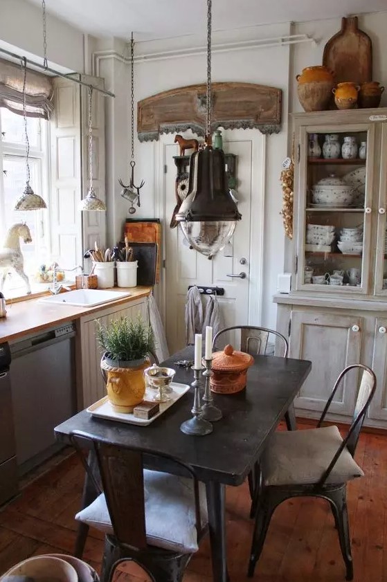 an industrial dining space right in the kitchen, with a black metal table and chairs, metal pendant lamps and potted plants