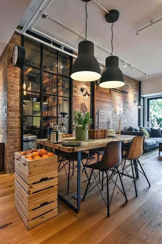an industrial dining spot with a wood and metal table, cool chairs, crates with fruit, black metal pendant lamps