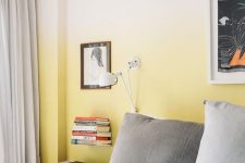 an ombre yellow accent wall is a great idea in a grey bedroom, and lots of books and lamps add to the decor of the space