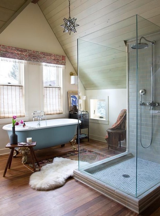 an opulent eclectic bathroom with touches of powder blue, a tiled shower, boho rugs and a boho printed curtain
