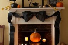 elegant vintage Halloween decor with candles and a pumpkin in the fireplace, a black black bow, blackbirds, pumpkins and leaves