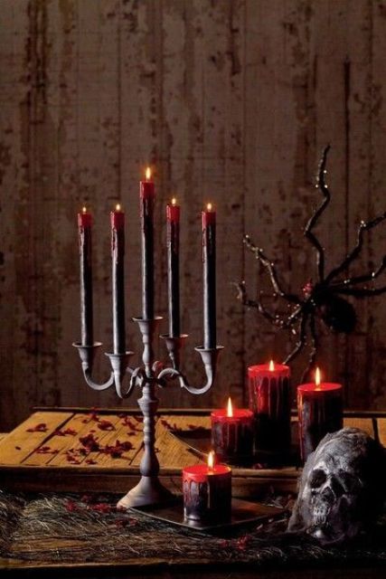gorgeous Halloween decor with a black candelabra and deep red candles, black and bloody candles, a black skull and a spider