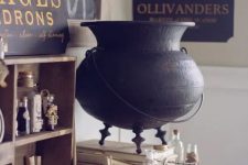 lovely vintage Halloween decor inspired by Harry Potter books with a wooden shelf, bottles and a bird, a witch’s cauldron, some signs