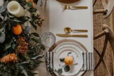 02 a beautiful Thanksgiving tablescape with striped napkins, gold cutlery, a greenery runner, blooms, citrus and candles