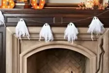 02 a cheesecloth ghost garland over the fireplace and a pumpkin display inside it are a great combo for Halloween