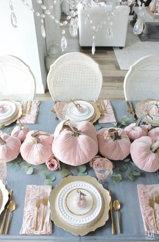 a chic and beautiful Thanksgiving tablescape with a grey tablecloth, pink velvet pumpkins and napkins, gold chargers and cutlery plus greenery