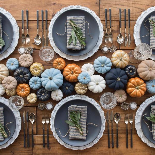a chic Thanksgiving tablescape with lots of blue, orange, white, tan and gold pumpkins, black plates and black cutlery