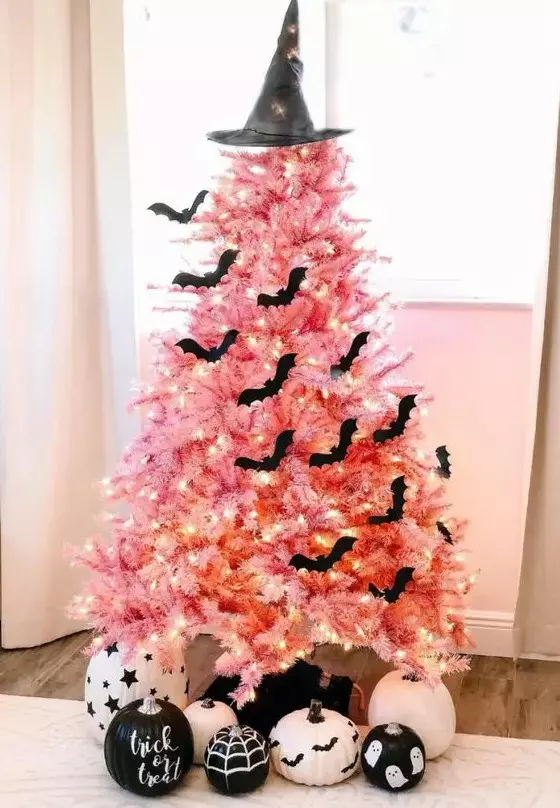 a beautiful pink Halloween tree with lights, black bats, a witch hat and black and white pumpkins is adorable
