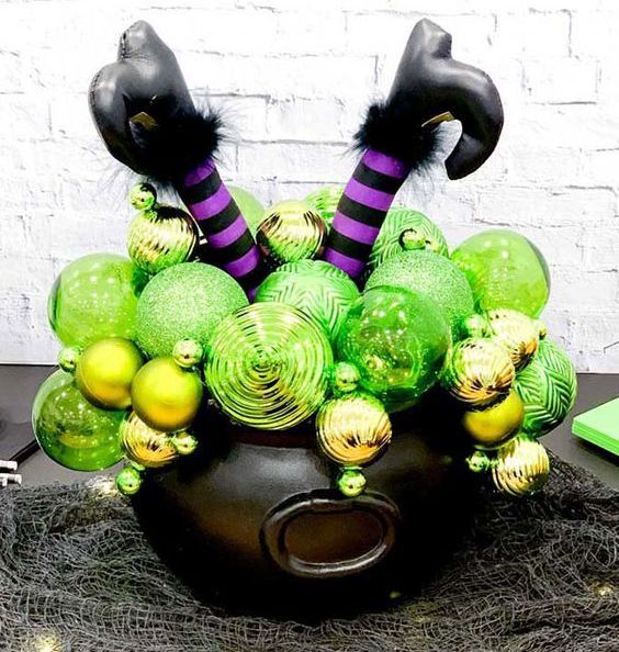 a black cauldron with neon green ornaments and witch's legs in funny boots is an easy centerpiece or decoration that can be DIYed for Halloween