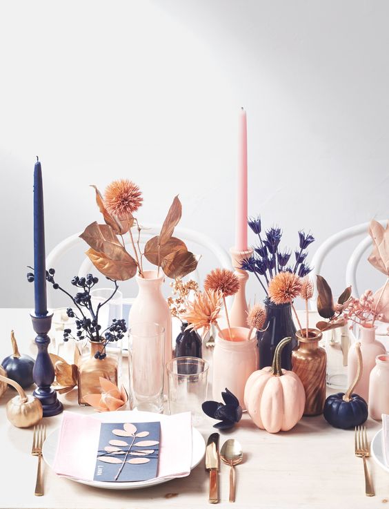a lovely modern Thanksgiving tablescape with neutral plates and pink napkins, pink and navy candles, pink and navy vases, spray painted grasses