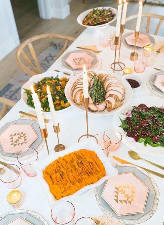 a lovely Thanksgiving tablescape with hexagon plates and menus, gilded candleholders, candles and pink glasses