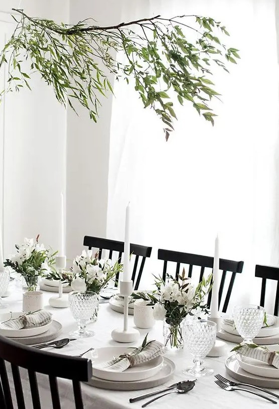 a modern and very neutral Thanksgiving tablescape with neutral porcelain and linens, greenery and white blooms plus white candles