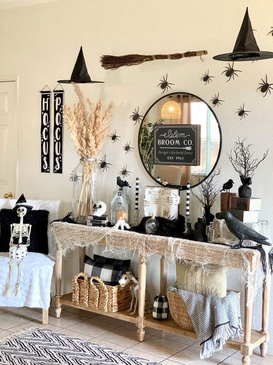 witch entryway styling with a console with blackbirds, spiders, a broom and witches' hats over the table and some skeletons