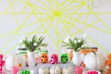 17 a bright neon Halloween party space with a yellow spiderweb, bold yarn covering the chairs and bright table decor