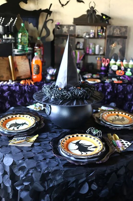 witches-inspired table decor with printed plates, a cauldron covered with a witch's hat with spiders is cool for Halloween