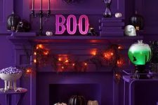 18 a chic purple Halloween space done with lights, pumpkins and black candles, a pink neon bat, a neon green drink in a tank