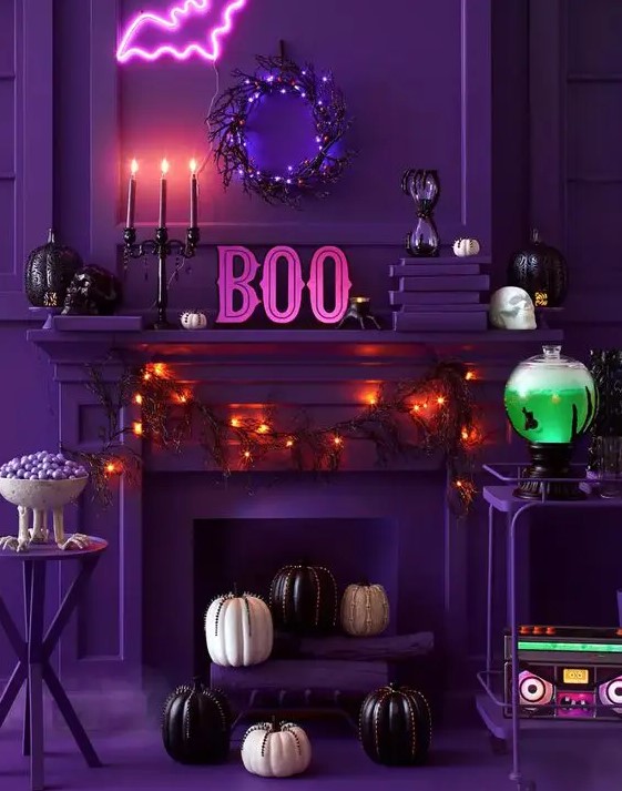 a chic purple Halloween space done with lights, pumpkins and black candles, a pink neon bat, a neon green drink in a tank