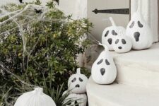 18 white pumpkins and gourds imitating Halloween jack-o-lanterns are an easy craft that you can make without any carving