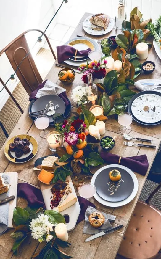 a modern super bold Thanksgiving tablescape with foliage, bold leaves, deep purple napkins and white and black plates