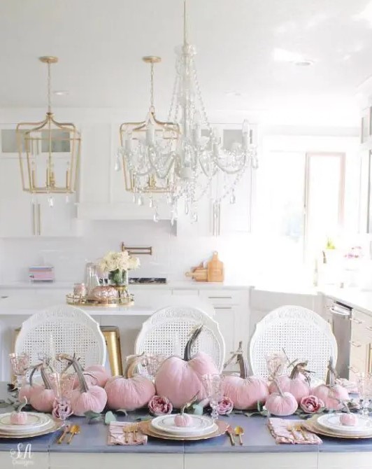 a super glam Thanksgiving tablescape with pink vlevet pumpkins and pink peonies, gold chargers and cutlery and mini pumpkins on each place setting