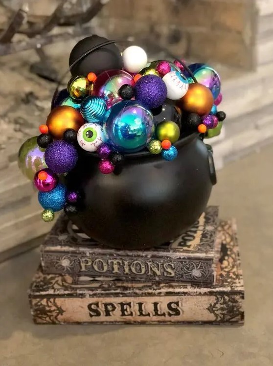 a couple of spellbooks with a cauldron on top and colorful eyeballs and ornaments for a lovely and whimsy Halloween decoration