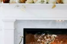 23 a glam Thanksgiving mantel with white, rust and burgundy velvet pumpkins, gilded leaves and pretty fabric pumpkins in front of it