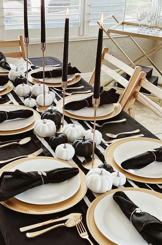 a monochromatic and simple Thanksgiving tablescape with dark linens, black and white pumpkins, gold chargers and cutlery