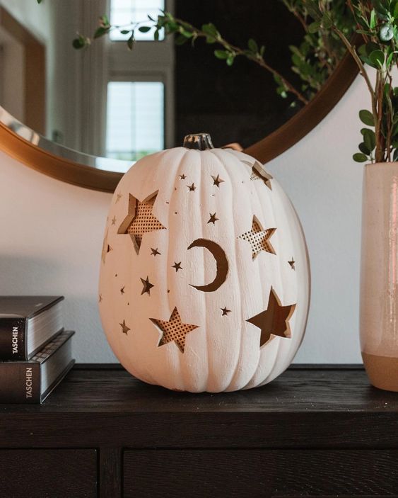 a white Halloween pumpkin with carved stars and moons can be used as a luminary or just as decor