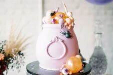25 a pink cauldron with candies and sweets in pastel colors is a great way to serve some food in a truly Halloween way