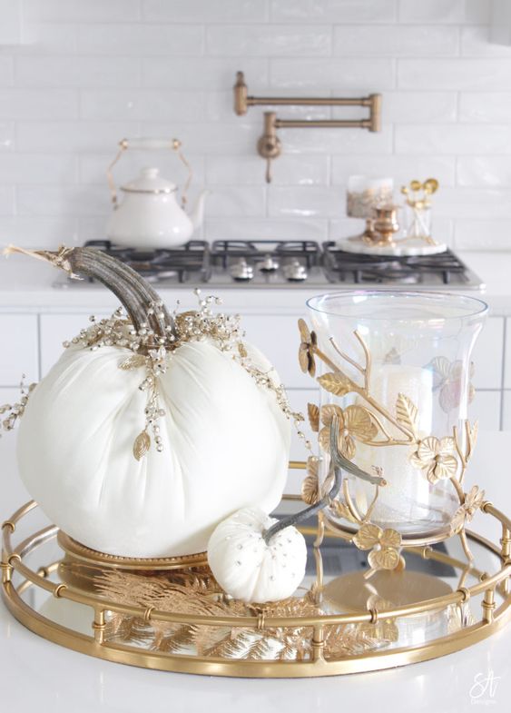 an elegant tray with white fabric pumpkins topped with rhinestones and pearls, a pillar candle in a candleholder